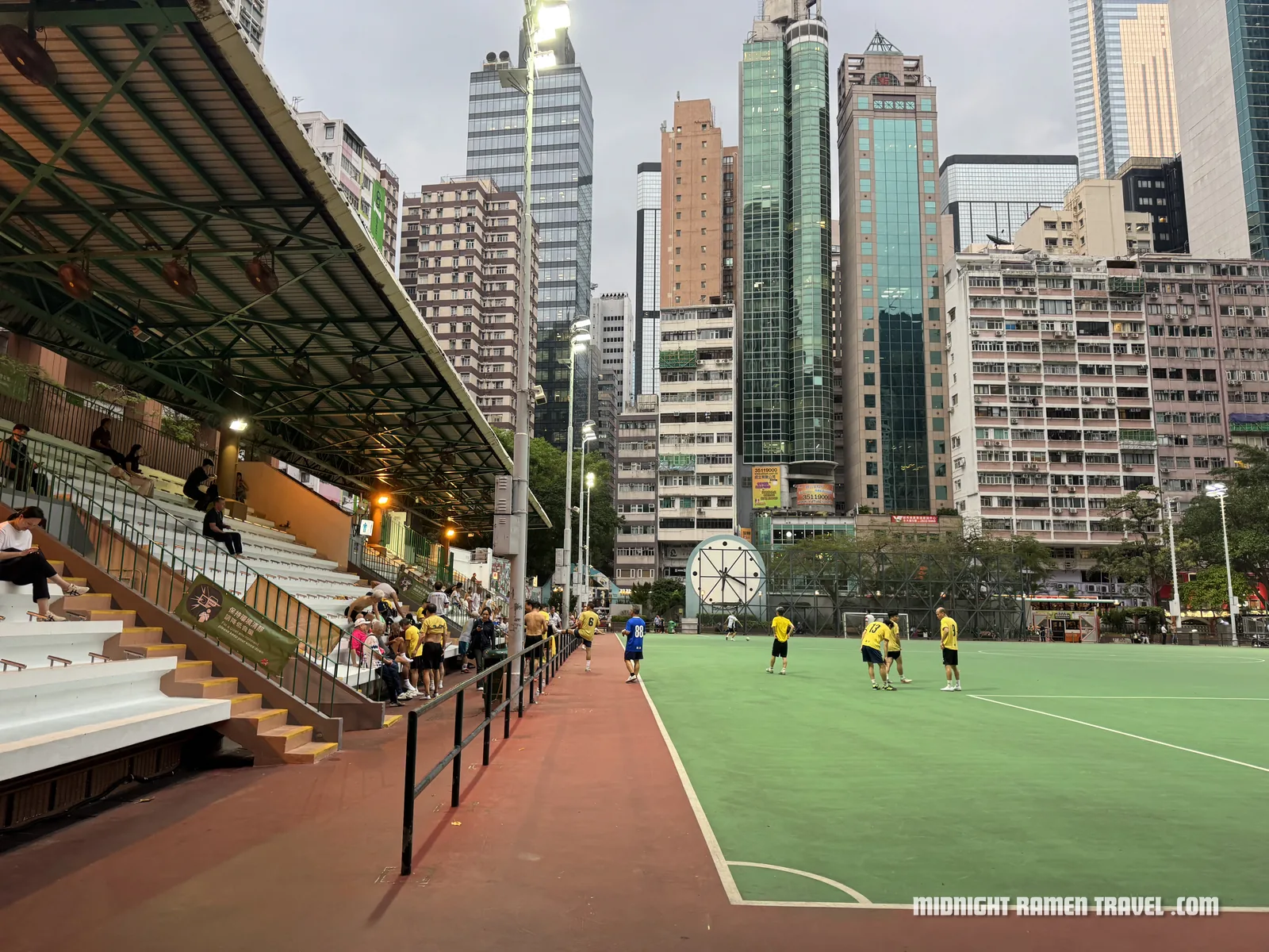 The locals playing soccer at night in Wan Chai, city backdrop